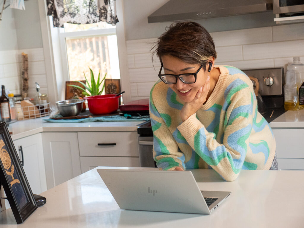 A female CNI student taking her class online while preparing dinner in her kitchen. 