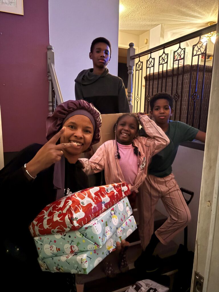 Lalla Zouboye, and her three happy children, pose with their gifts from their Christmas Cheer Board Hamper. 