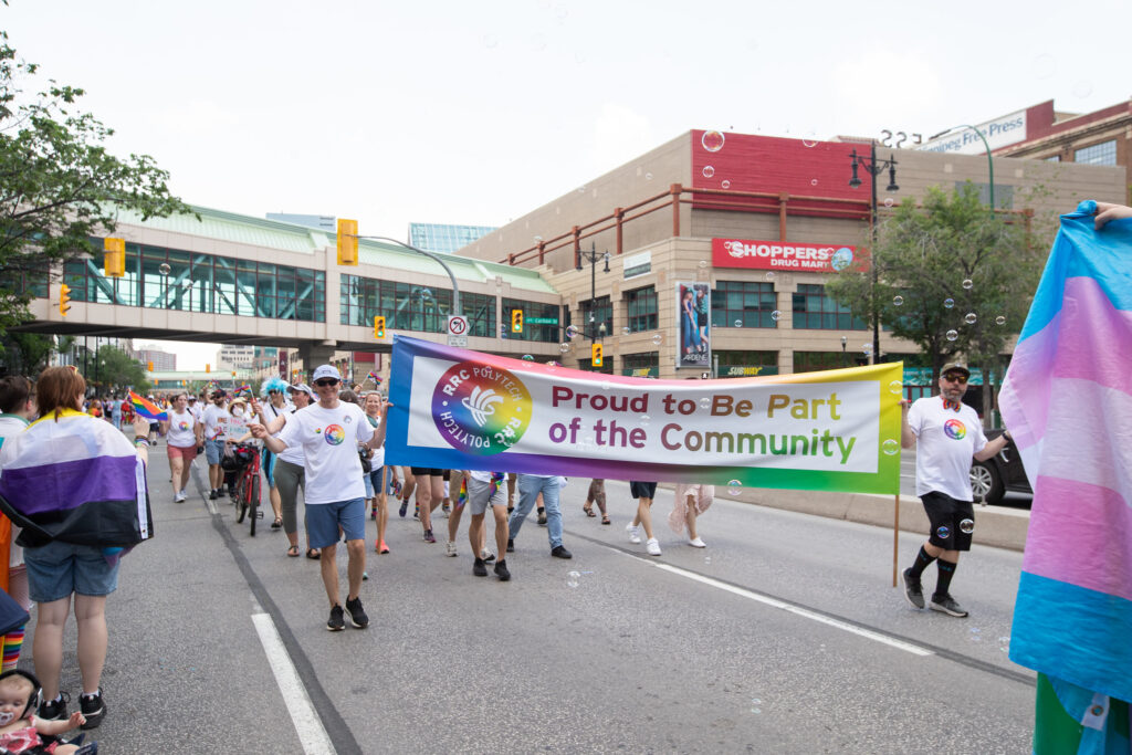 RRC Polytech Community taking part in Pride Parade holding a banner saying "Proud to be part of the Community"