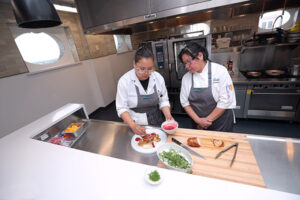 Two students cooking in a commercial kitchen