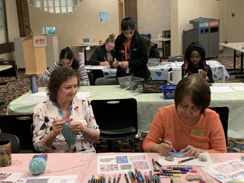 Group of students and staff crocheting, painting on rocks and colouring.