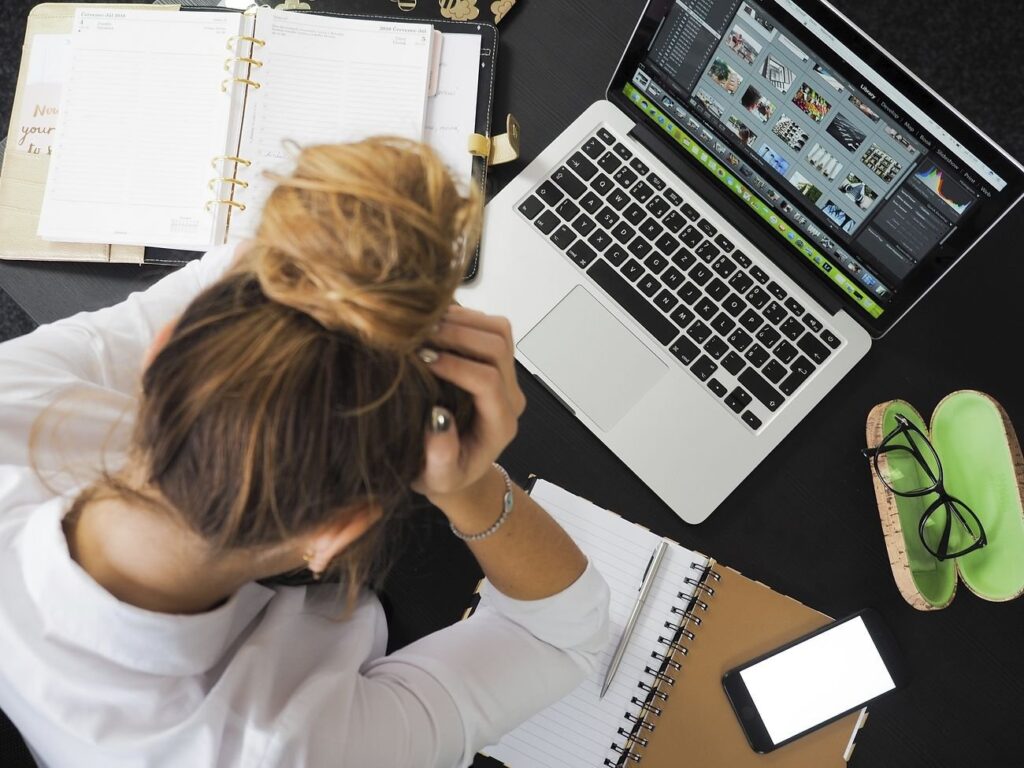 Stressed woman with her hands in her head working on a laptop.