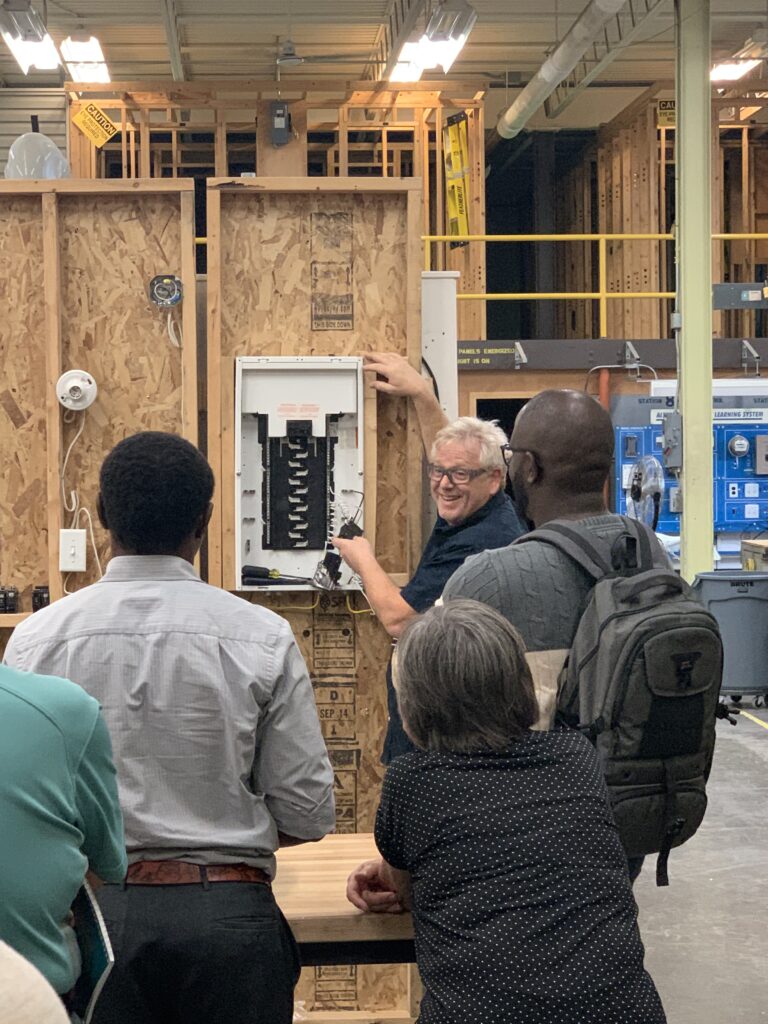 Electrician instructor showing a group a breaker panel.