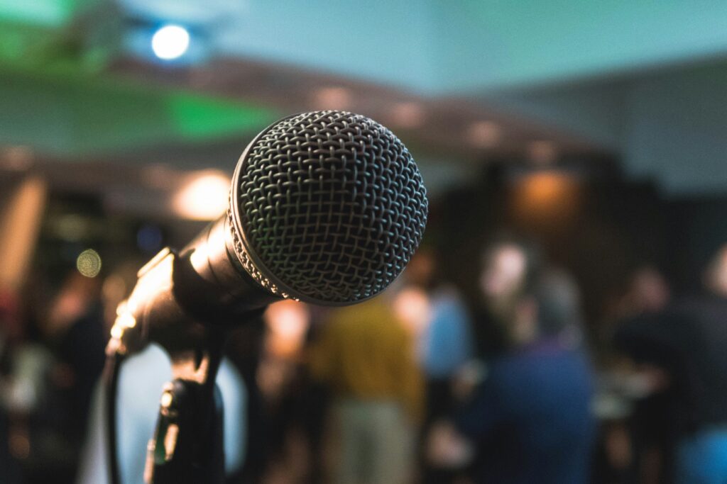 Microphone for singing looking at with blurred audience in background.