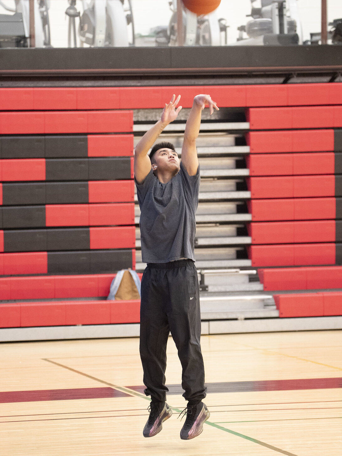 Student shooting a basketball into a hoop at the North Gym