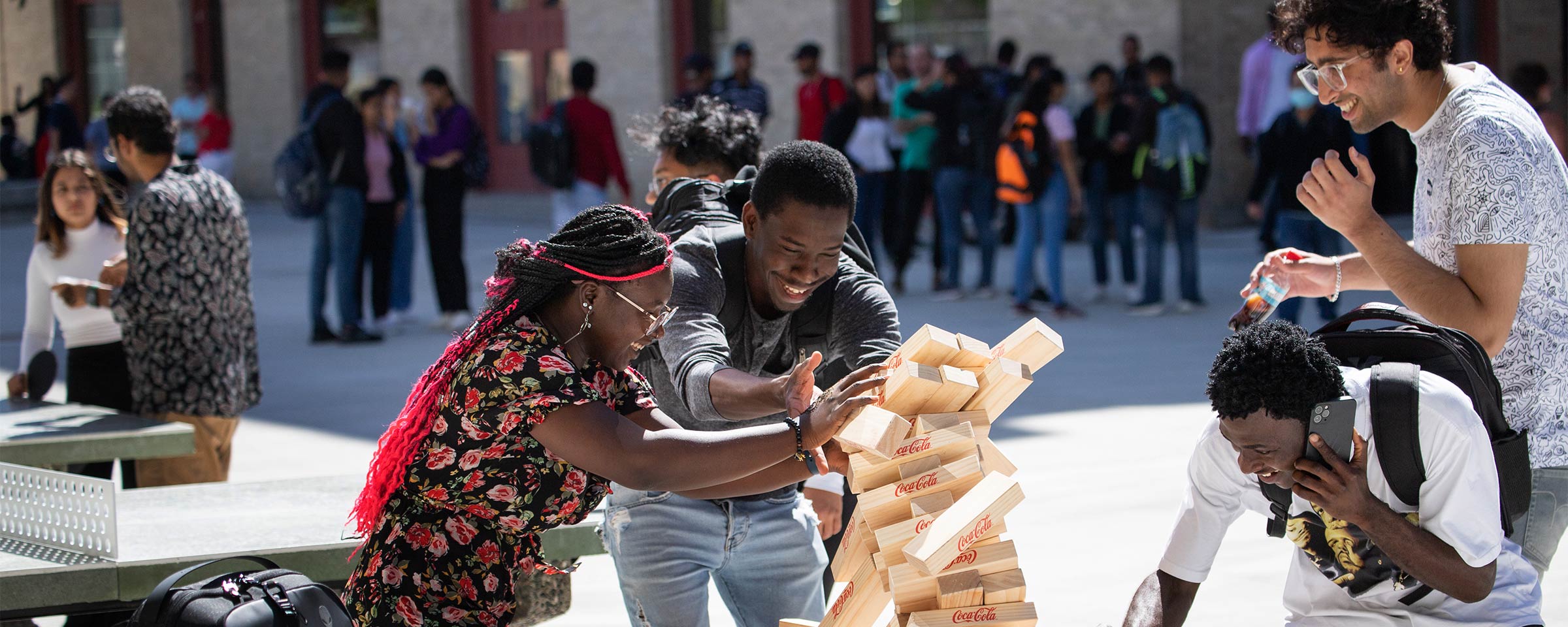 Four students playing outdoor Jenga game at Exchange District Campus courtyard