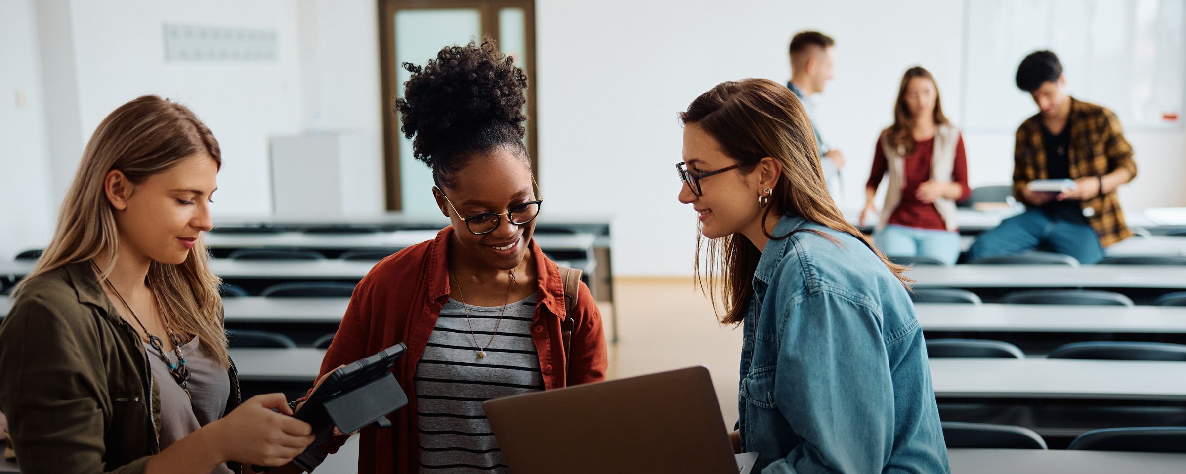 Three students talking to one another in a classroom