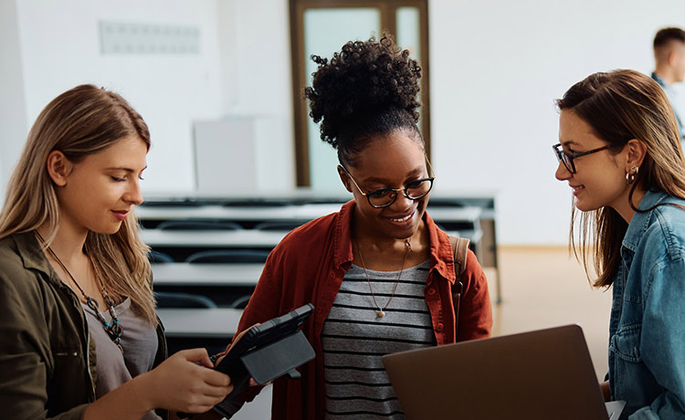 Three students talking to one another in a classroom