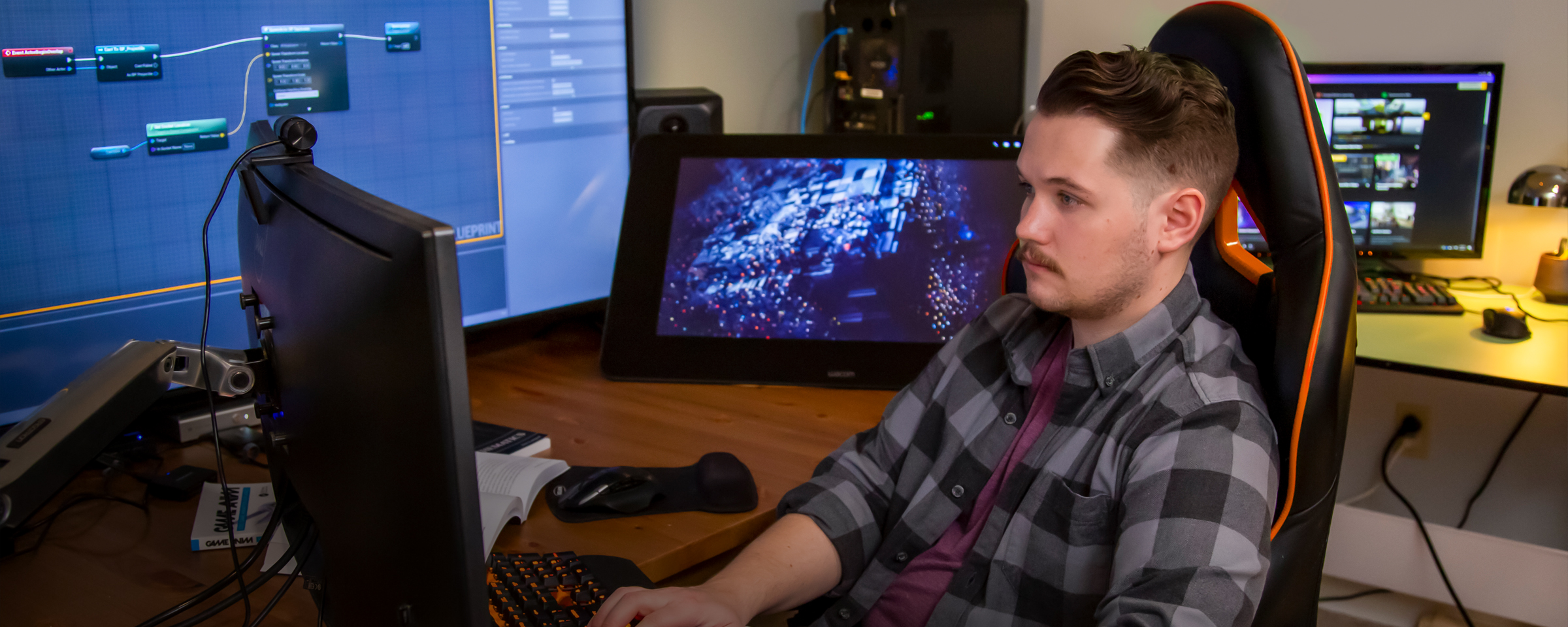 Student sitting at a computer with several monitors