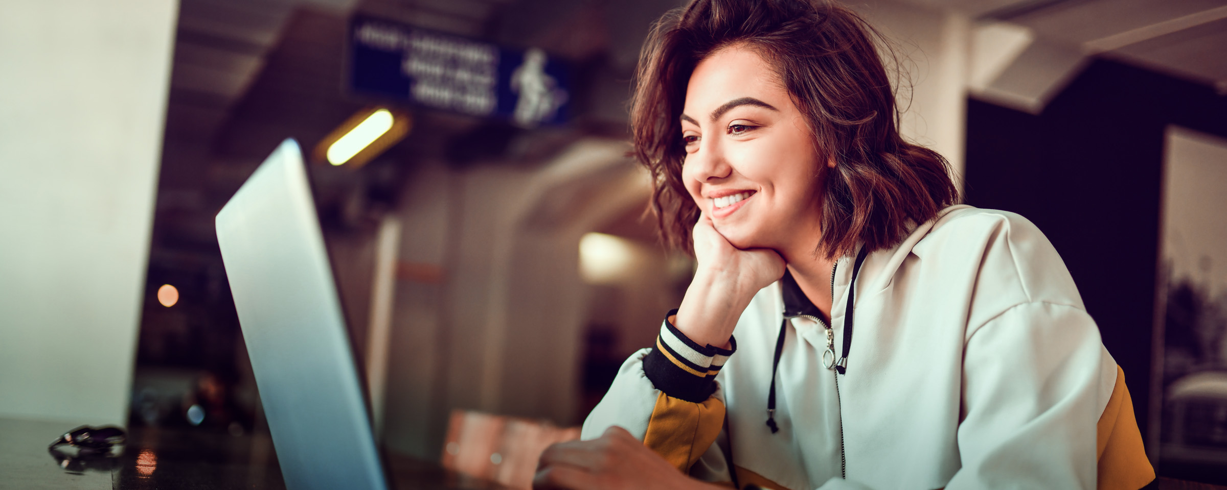 Smiling young woman working on laptop.