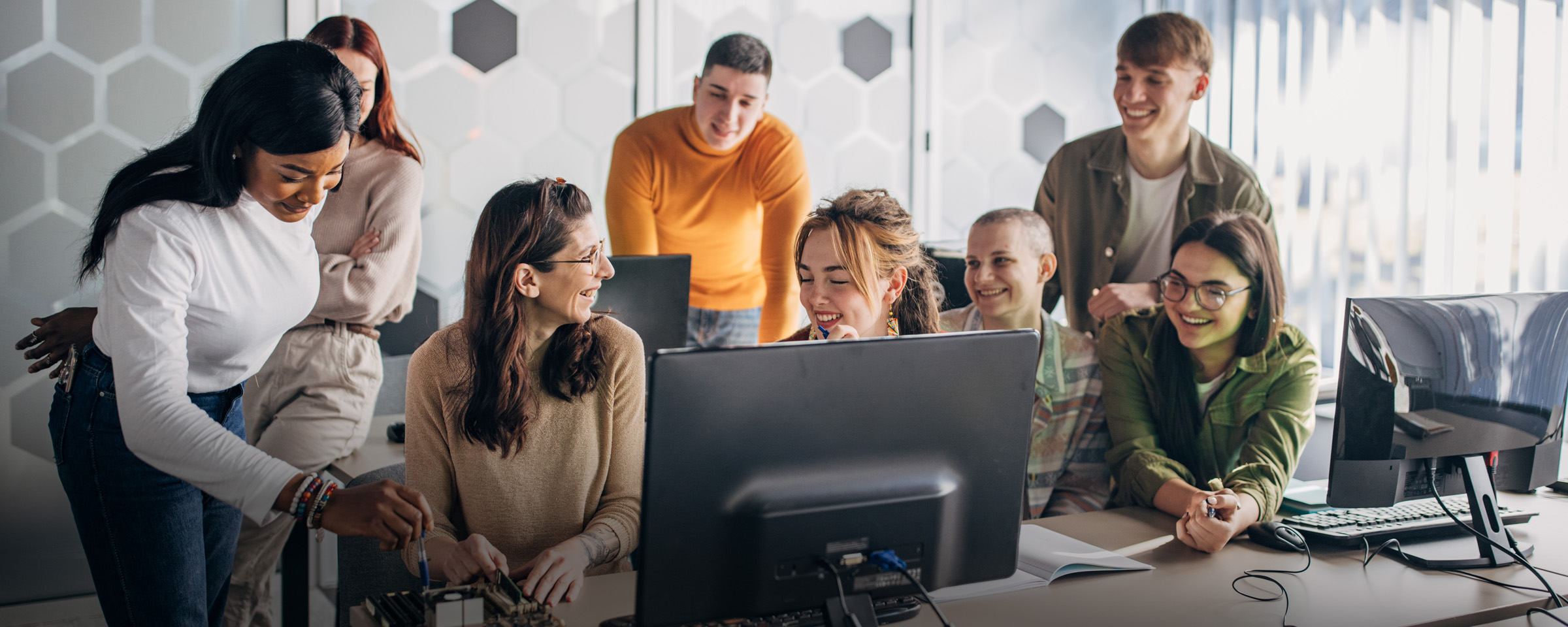 divers group of men and women, smiling while seated around a computer.