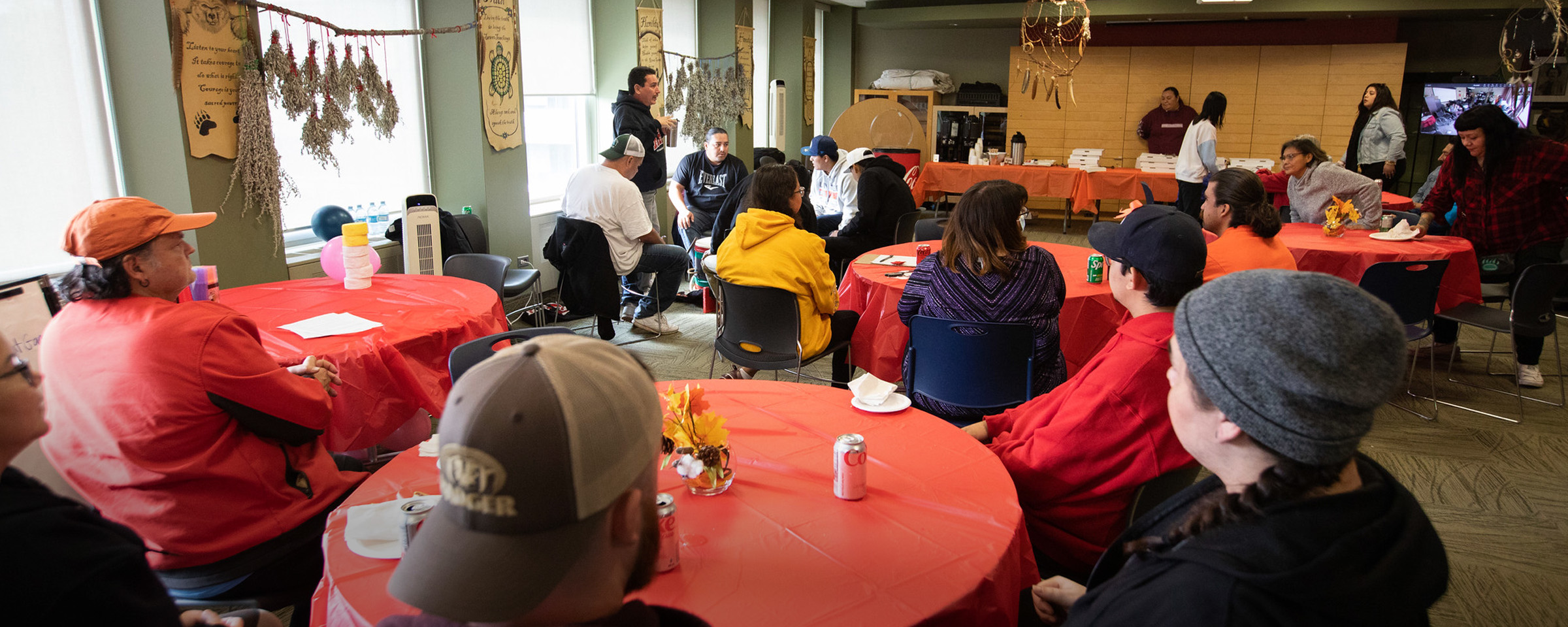 Students and staff members seated at tables with orange tablecloths.